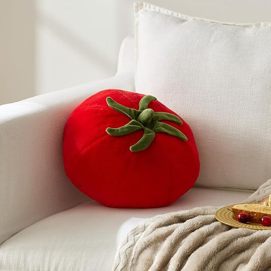 Red tomato-shaped pillow on a white couch with a neutral background